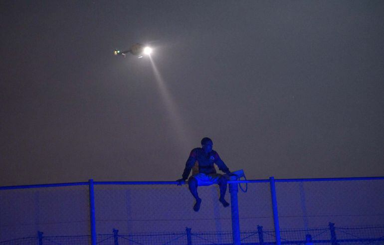 RNPS: YEAREND REVIEW 2014: HUMANITARIAN   An African migrant sits on top of a border fence covered in razor wire between Morocco and Spain&#039;s north African enclave of Melilla, during an attempt to cross into Spanish territory, in this June 14, 2014 file ph