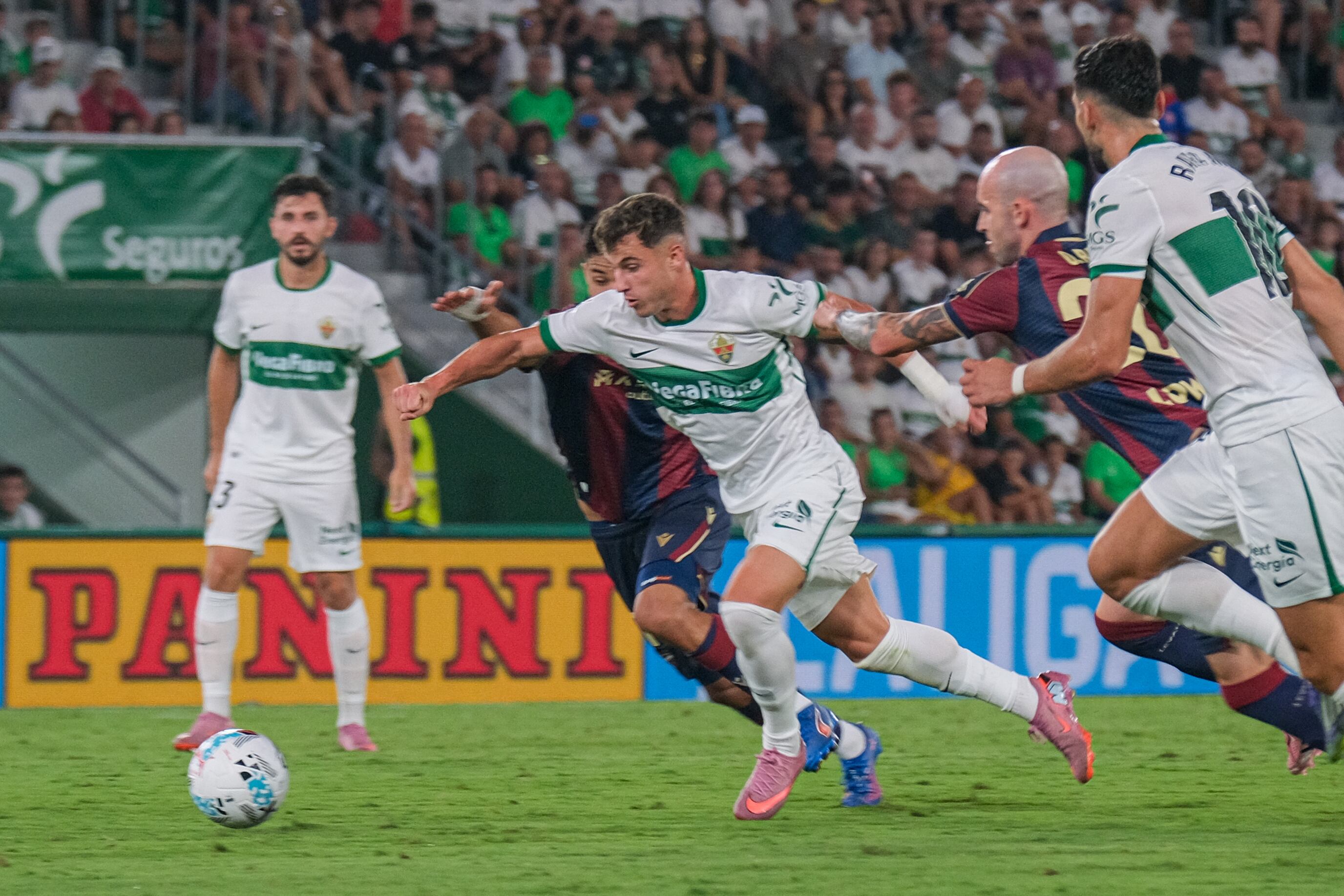 El centrocampista del Elche Germán Valera (c) pelea un balón con dos rivales del Levante durante el partido de la tercera jornada de LaLiga que Elche CF y Levante UD disputan este viernes en el estadio Martínez Valero. EFE/ Pablo Miranzo.
