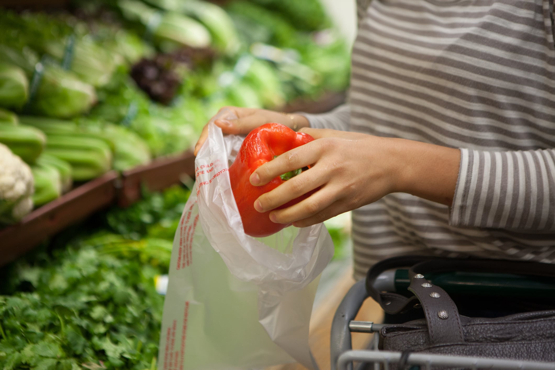 Una mujer guarda un pimiento en una bolsa compostable.