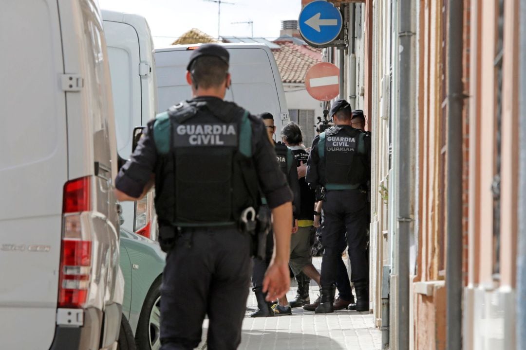 Agentes de la Guardia Civil acompañan a uno de los nueve detenidos durante el registro de un domicilio en Sabadell (Barcelona)