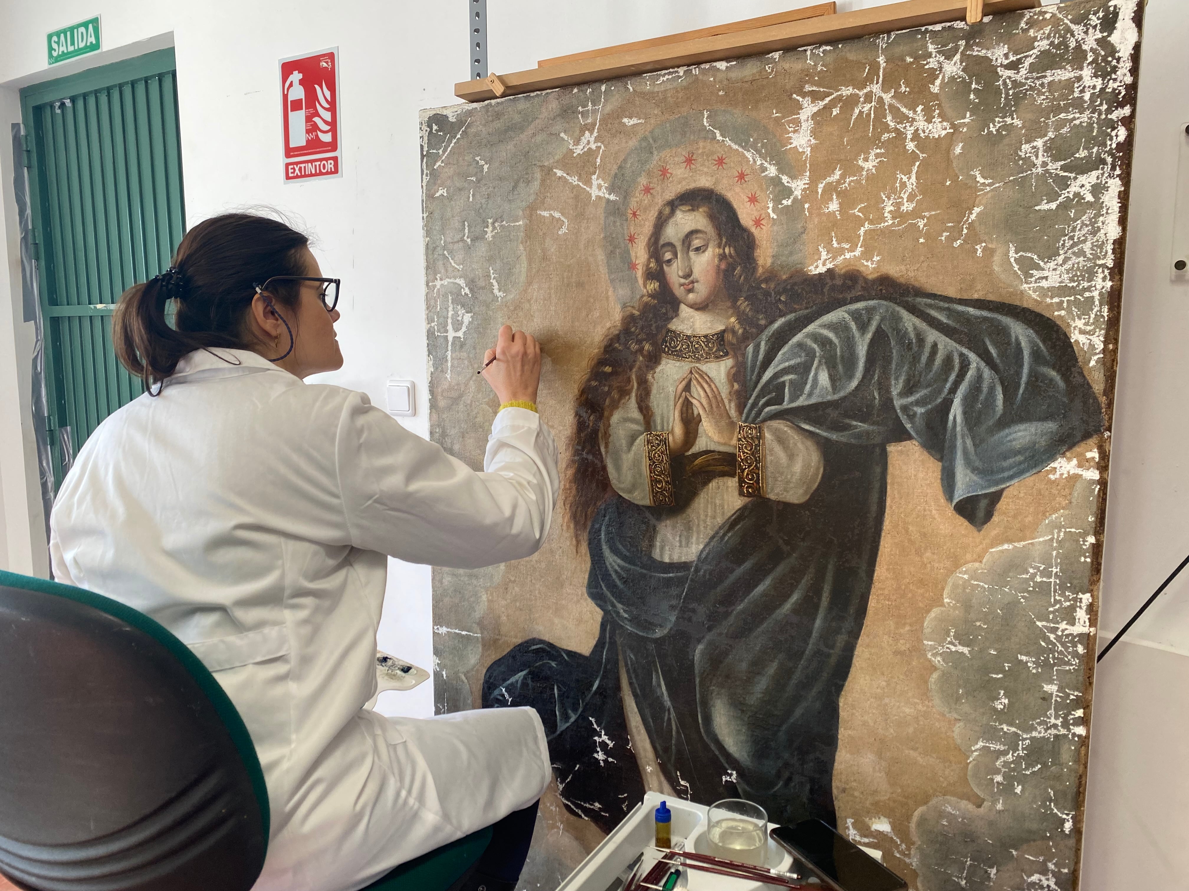 Cristina Checa trabaja en la restauración de un cuadro del siglo XVII que representa a una Inmaculada.