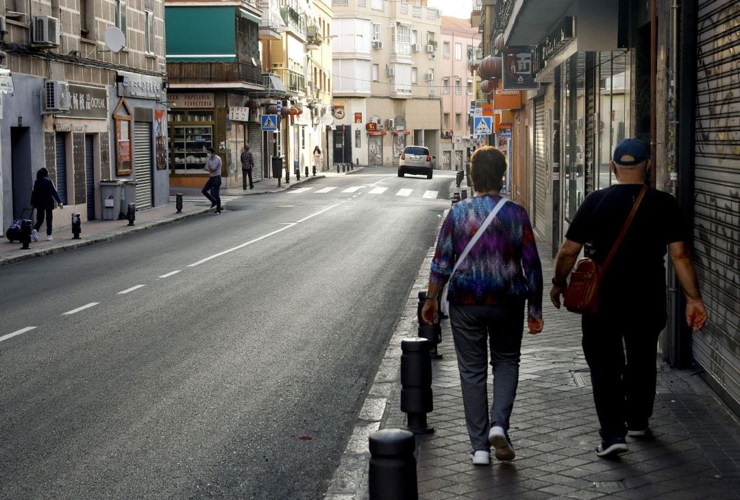 Una pareja camina por una calle de Usera, uno de los barrios afectados por las restricciones sanitarias en Madrid