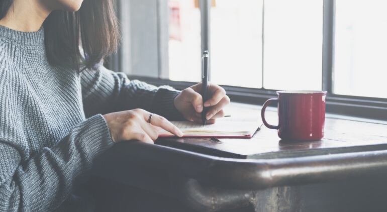 Una mujer escribiendo en un cuaderno