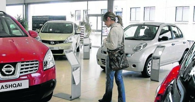 Un cliente comprueba el precio de un vehículo en un concesionario de coches