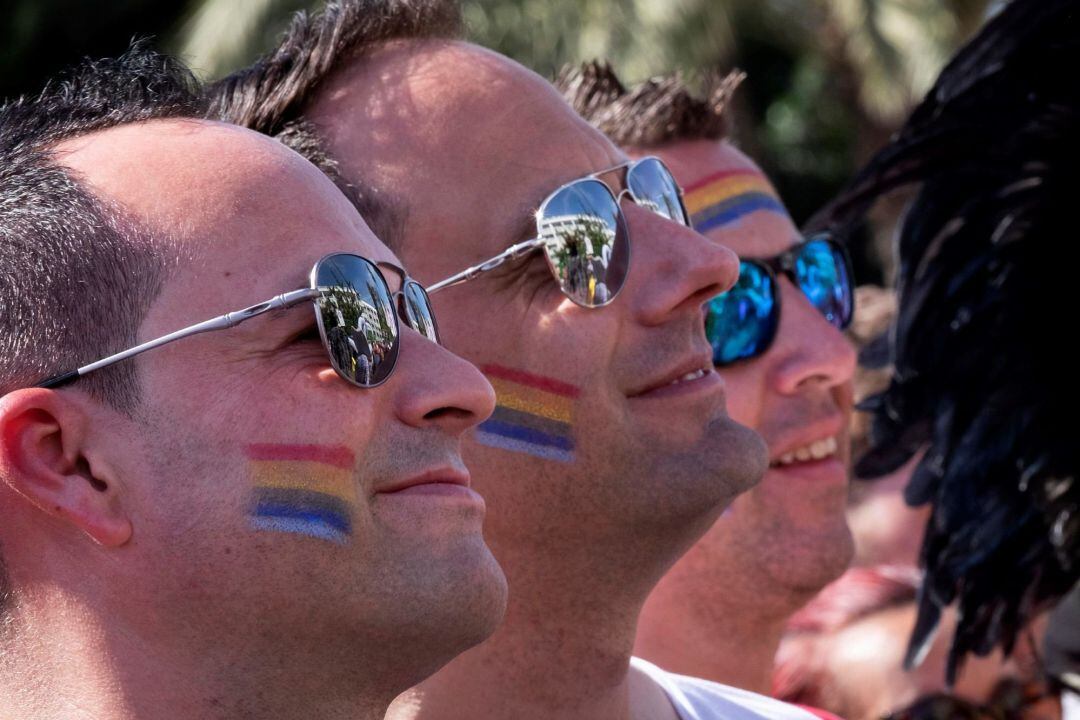 Tres hombres portan en su rostro la bandera multicolor