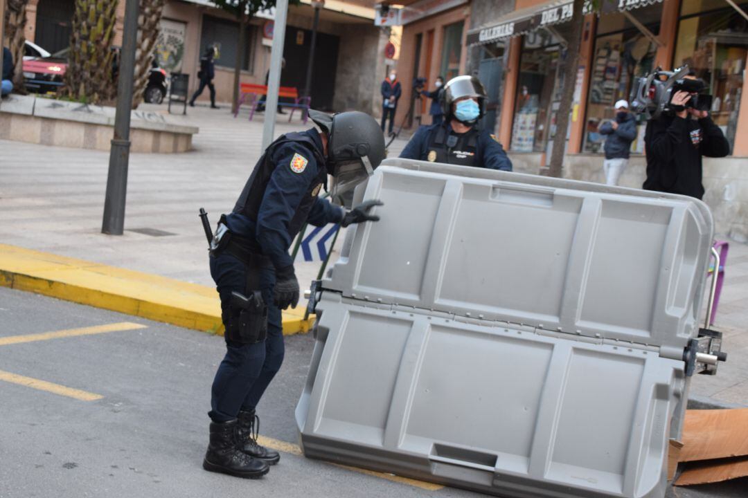 Policías recogen un contedor volcado en las protestas.
