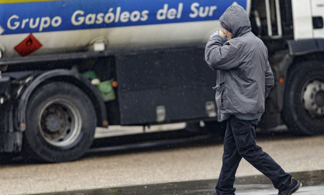 Un hombre pasa al lado de un camión de suministro de gasóleo en una estación de servicio.