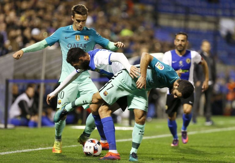 Los jugadores del FC Barcelona, Álex Carbonell (i) y el turco Arda Turan (d), luchan el balón con Rojas, del Hércules, durante el encuentro correspondiente a la ida de los dieciseisavos de final de la Copa del Rey que se disputa esta noche en el estadio J