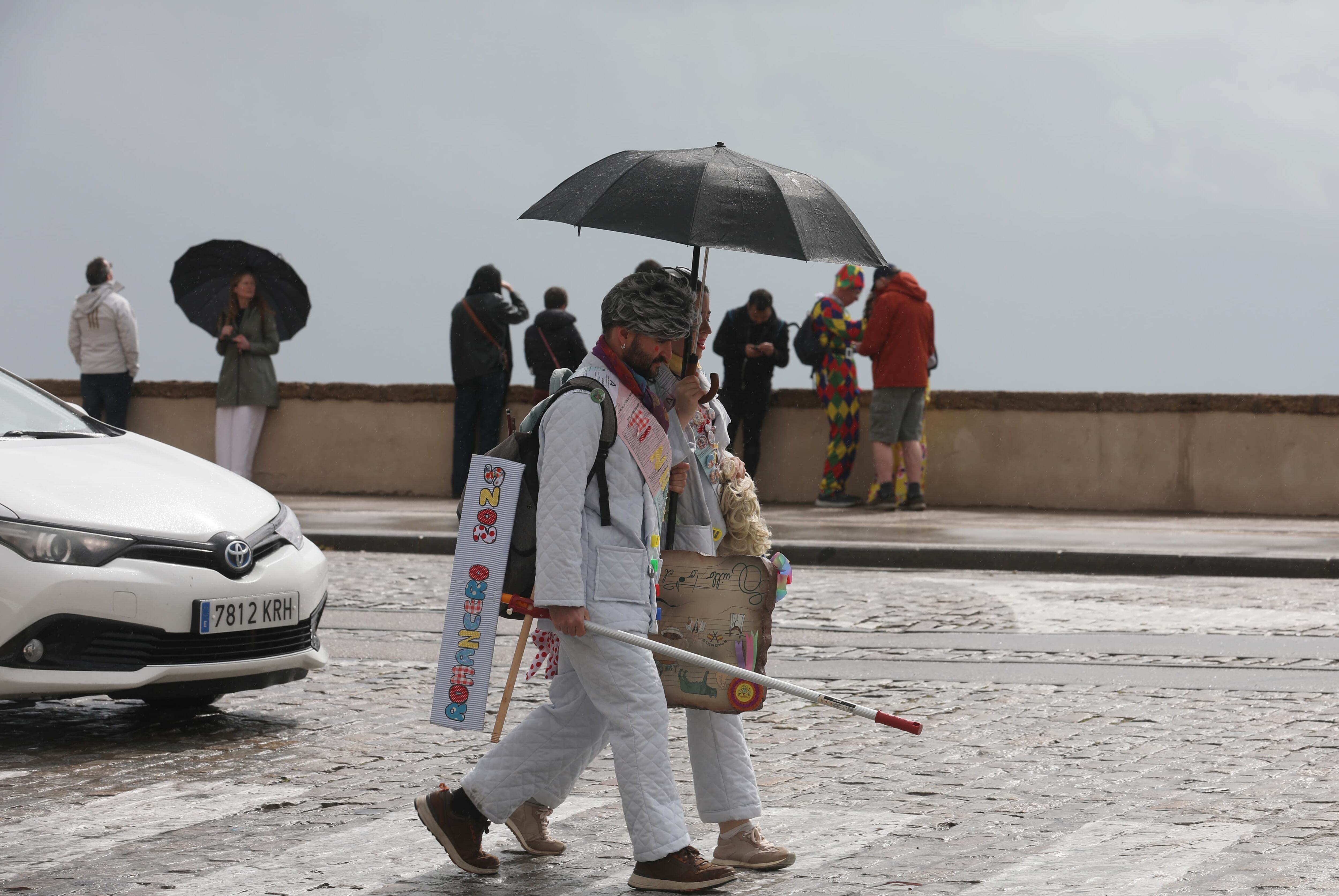 Dos personas con sus trajes de Carnaval en un día lluvioso en la última jornada del carnaval, este domingo en Cádiz. EFE/Román Ríos