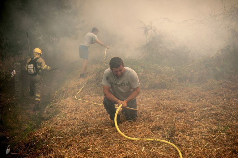 Un vecino ayuda en la extinción del incendio originado ayer en el ayuntamiento de Entrimo, en Ourense.