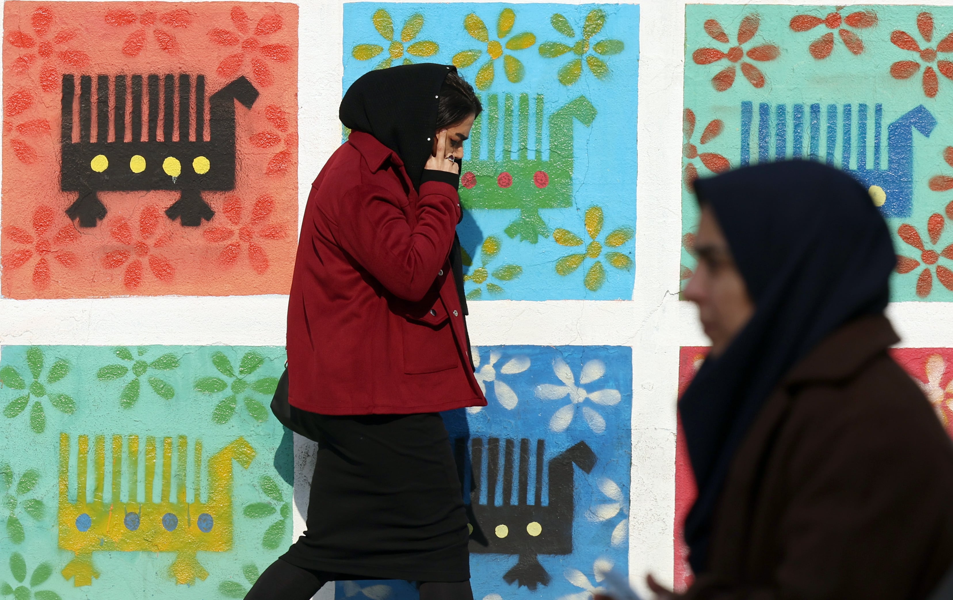 Una mujer Iraní hablando por teléfono pasa por delante de un mural en Teheran este mes de Diciembre