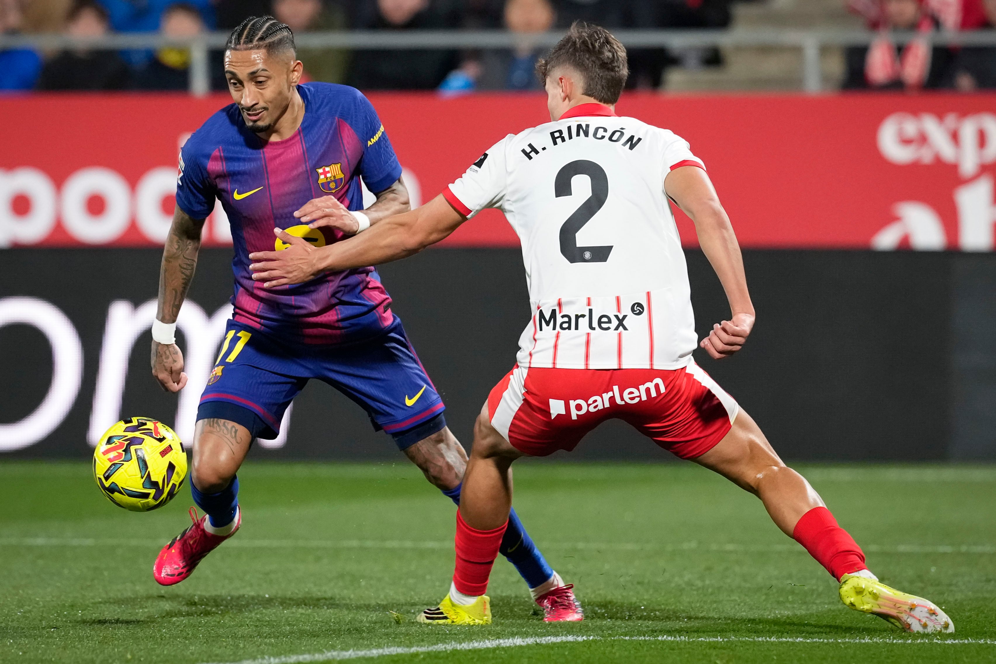 GIRONA, 16/02/2026.- El delantero brasileño del FC Barcelona, Raphinha (i), intenta llevarse el balón ante el defensa del Girona, Hugo Rincón, durante el partido de LaLiga de fútbol que Girona FC y FC Barcelona disputan este lunes en el estadio de Moltilivi. EFE/David Borrat.