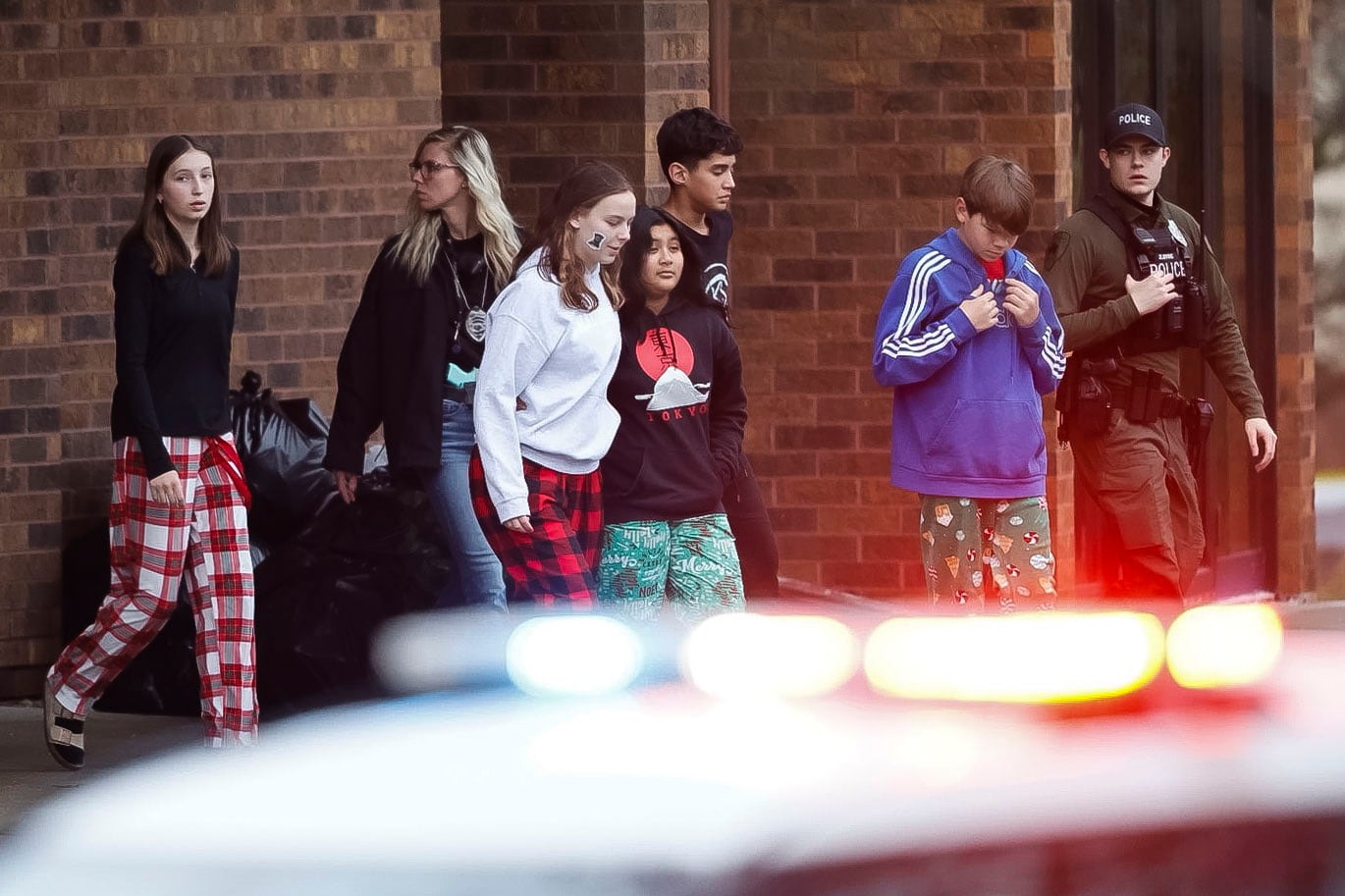 Adultos y estudiantes afuera de una iglesia en los terrenos de Abundant Life Christian School después de un tiroteo ese mismo día en Madison, Wisconsin