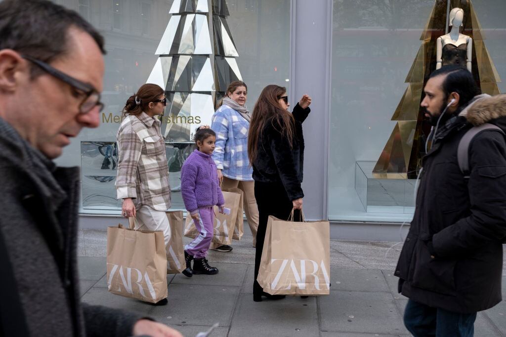 Compradores de Zara pasean por la calle.