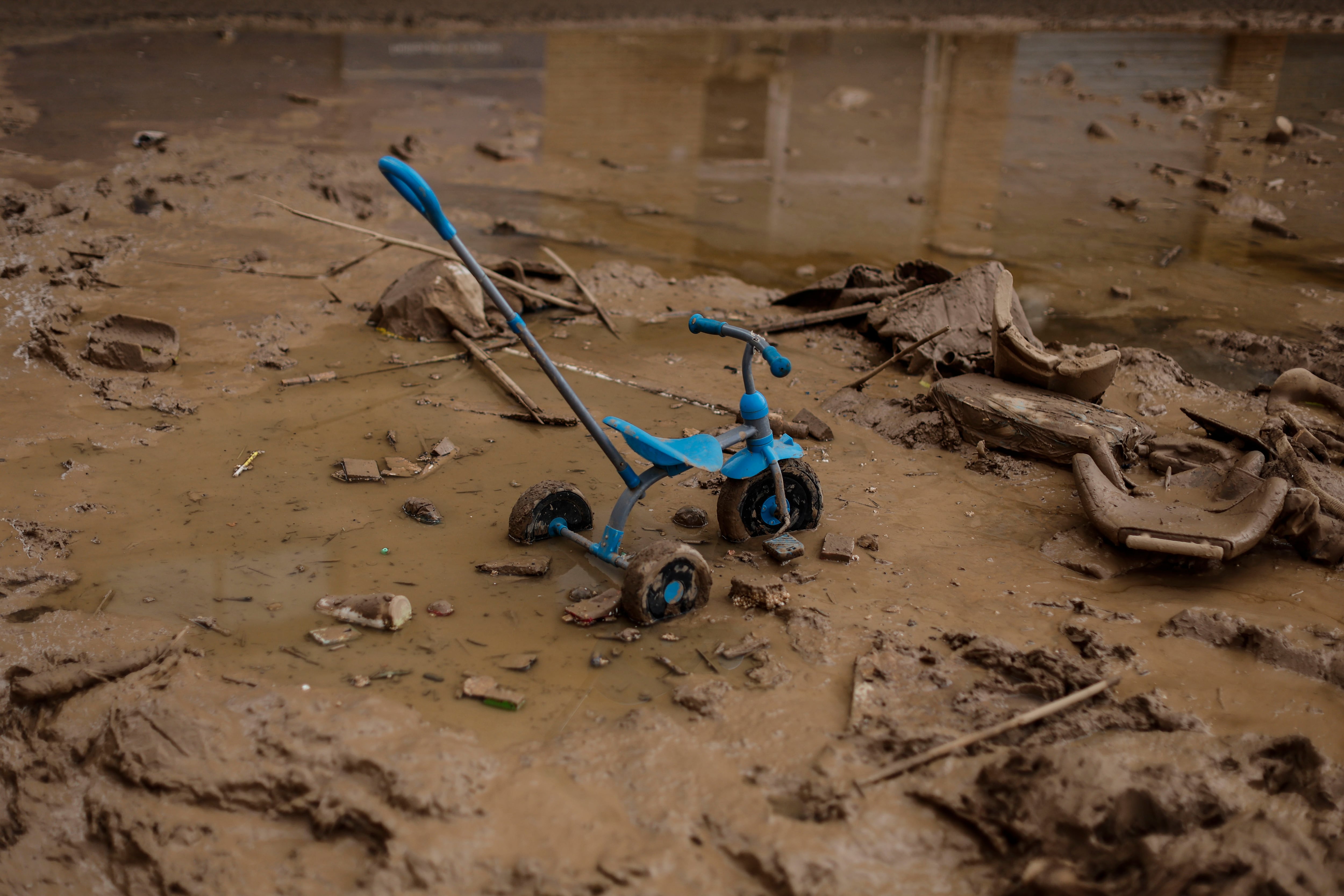 PAIPORTA(VALENCIA), 18/11/2024.- El triciclo de un niño sobre en barro de una calle de Paiporta, este lunes. Una decena de centros educativos de municipios de la zona cero de la dana que asoló Valencia hace veinte días reinician sus clases en otro paso del lento camino hacia una cierta normalidad para las familias afectadas, mientras empresas y trabajadores reciben asesoramiento público para afrontar las consecuencias laborales de una tragedia que deja ya 219 víctimas mortales y 13 desaparecidos. EFE/Biel Aliño
