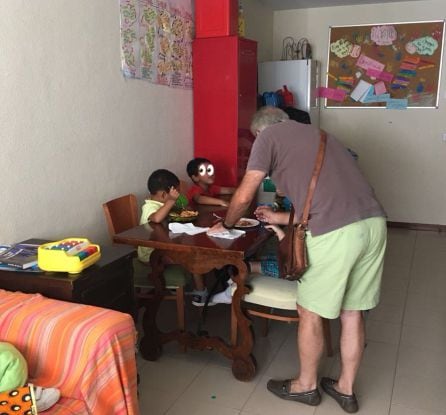 El voluntario Antonio de Francisco con dos niños en el desayuno de Pilar