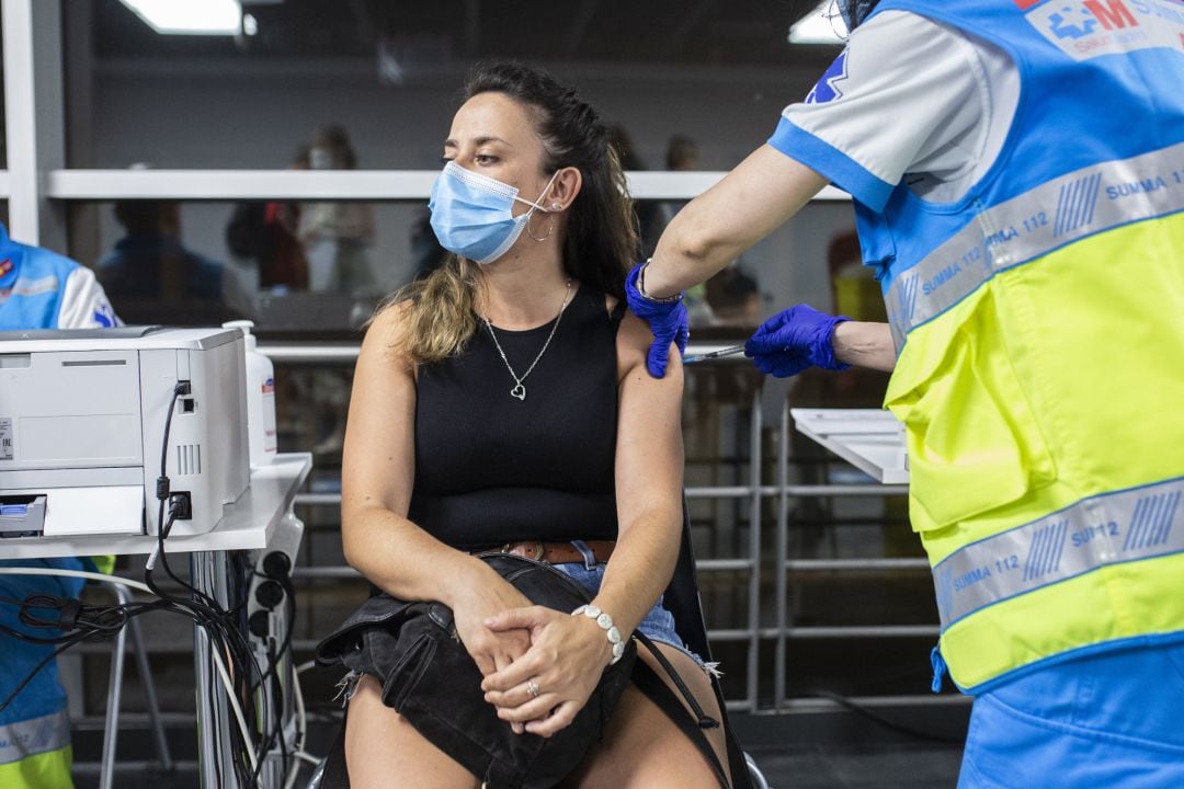 Un sanitario administra una dosis de la vacuna de Pfizer a una mujer en el Wizink Center