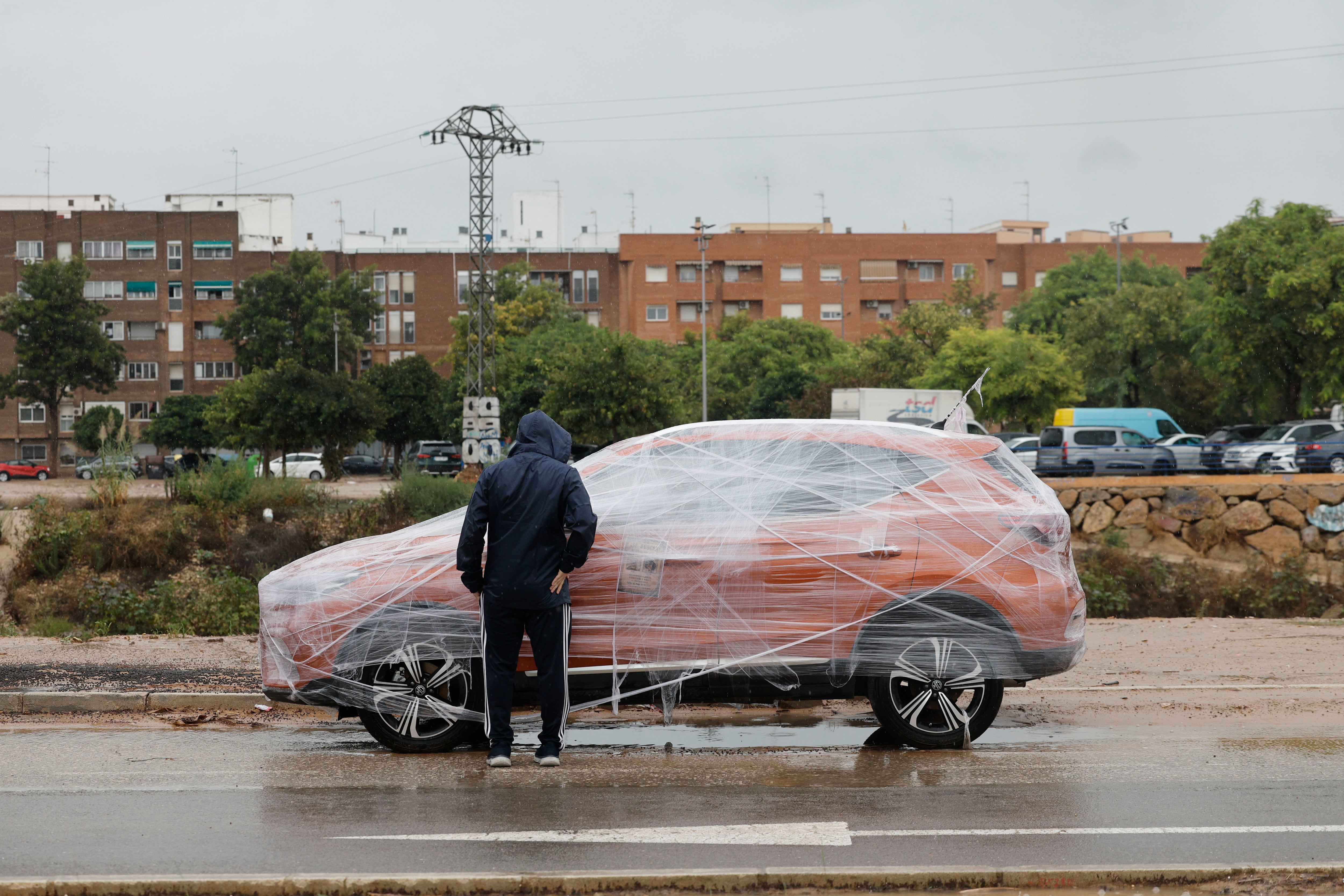 Un hombre observa un coche protegido para la lluvia en Catarroja (Valencia)