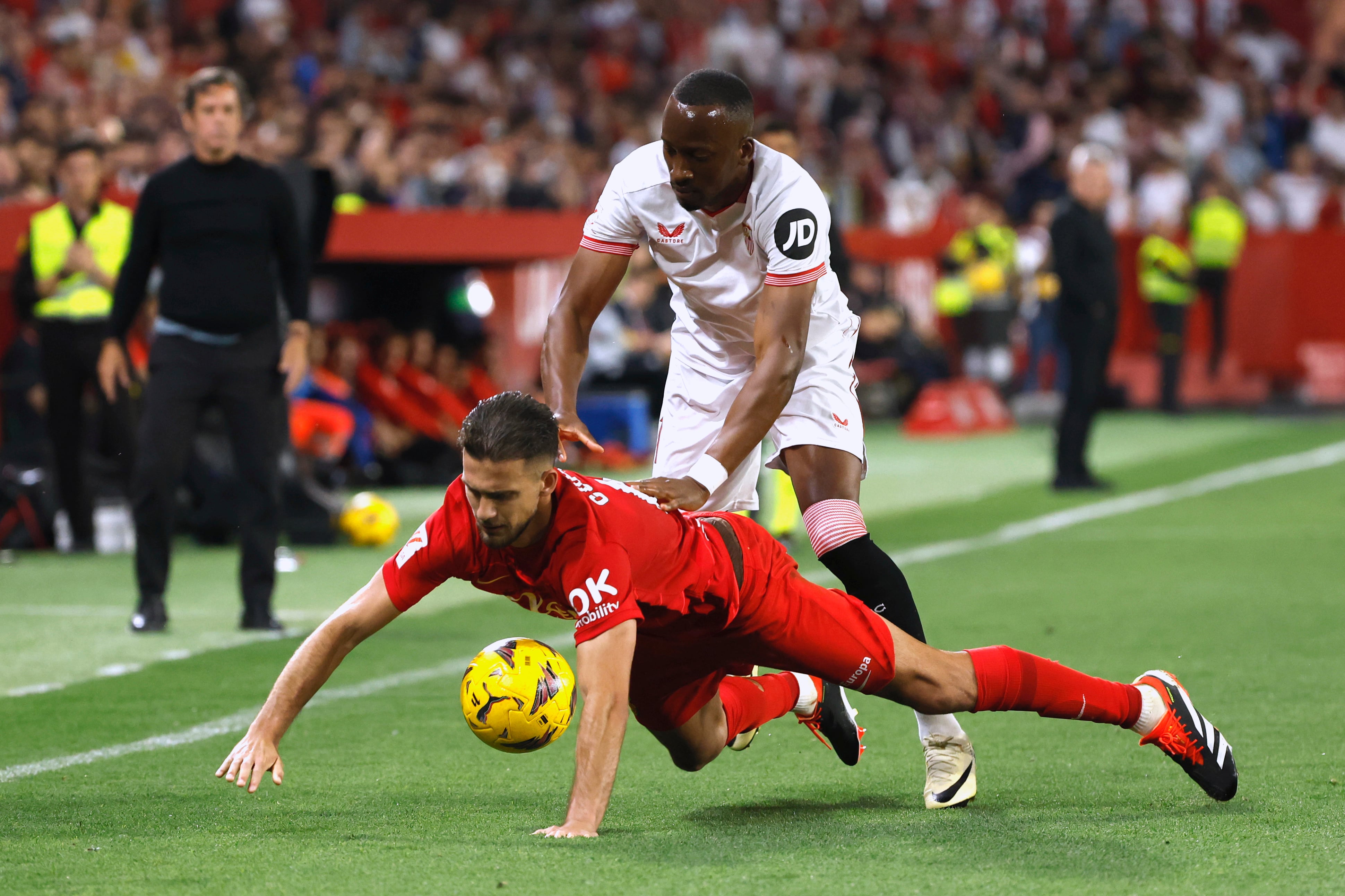 SEVILLA, 22/04/2024.- El defensa del Mallorca José Manuel Arias Copete (i) cae ante el belga Dodi Lukebakio, del Sevilla, durante el partido de la jornada 32 de LaLiga que Sevilla FC y RCD Mallorca juegan este lunes en el estadio Sánchez-Pizjuán de Sevilla. EFE/ Julio Muñoz
