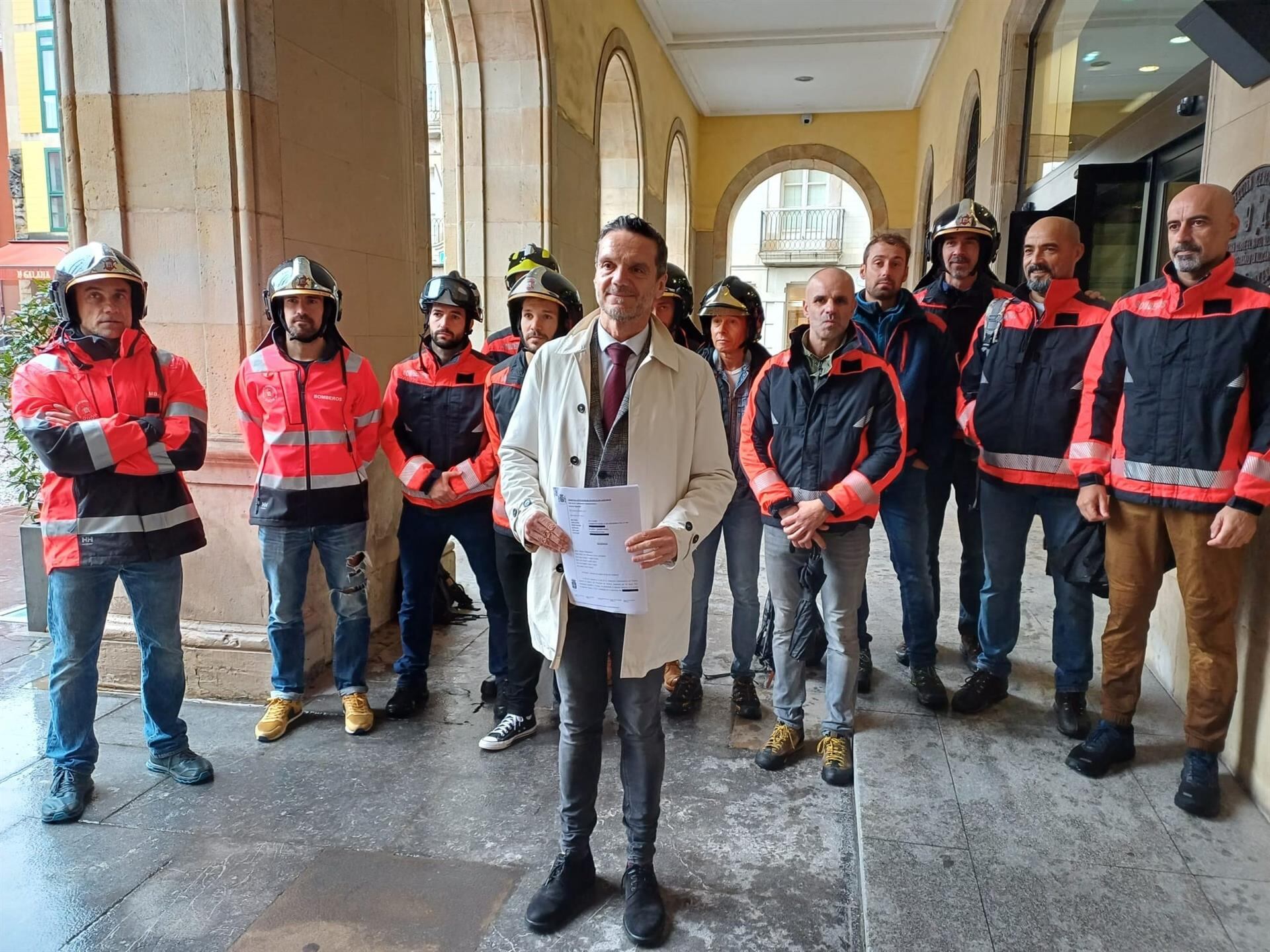 El abogado Javier Calzadilla, acompañado de bomberos de Gijón, frente al Ayuntamiento gijonés.