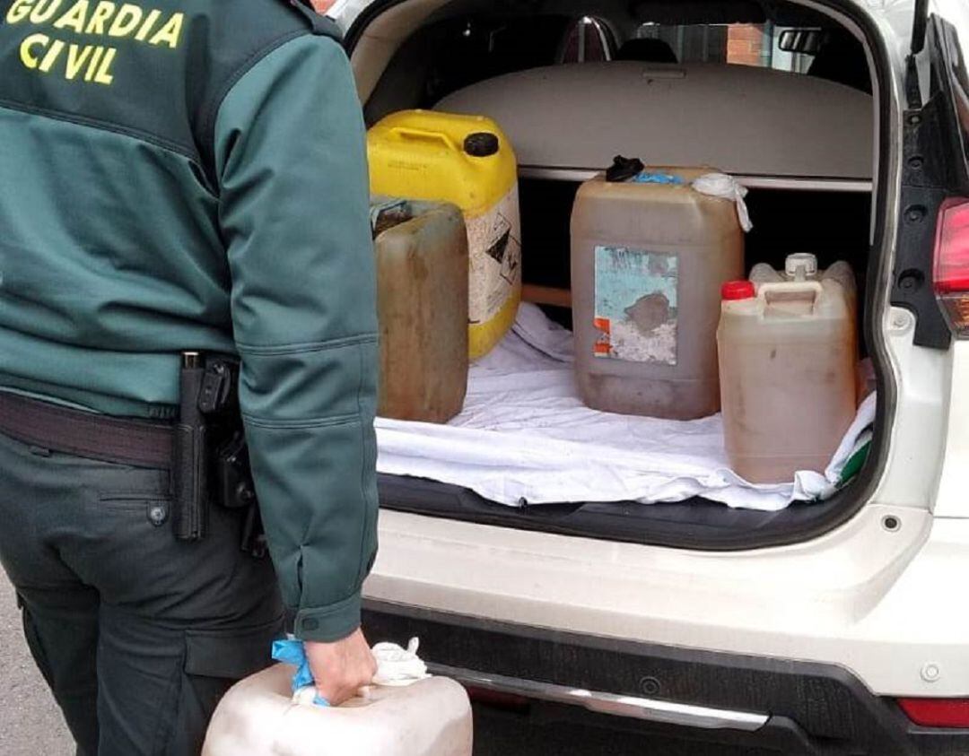 Un agente de la Guardia Civil recoge el gasoil incautado al sospechoso.