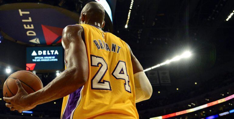 El jugador de los Lakers de Los Ángeles Kobe Bryant (dcha) se prepara para pasar la bola durante su partido de la NBA de baloncesto disputado contra los Kings de Sacramento en el pabellón Staples Center de Los Ángeles, California (Estados Unidos), el 9 de