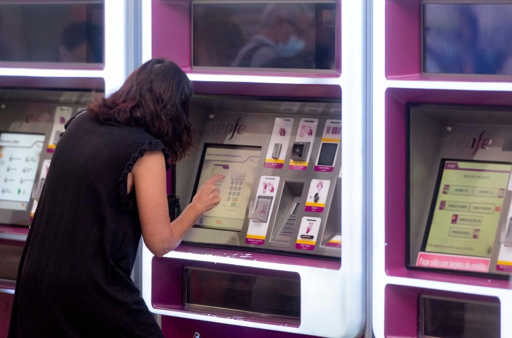 Una mujer compra un billete en una máquina de Renfe