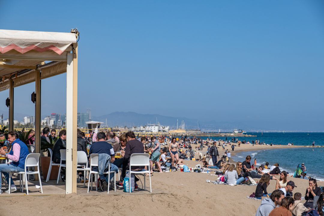 Clientes de un chiringuito de la Barceloneta, frente a la playa más popular de la capital catalana, este domingo.