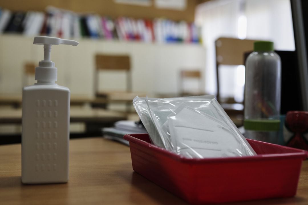 Mascarillas y gel desinfectante en la mesa de profesor de un aula