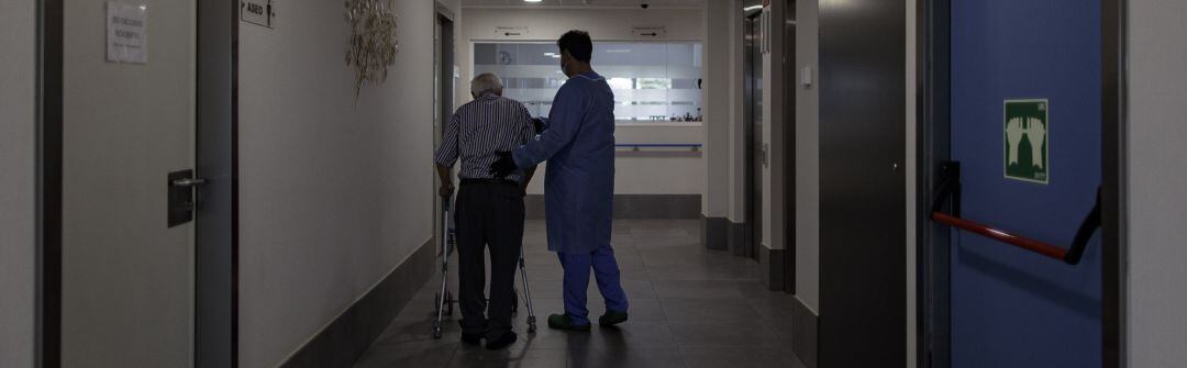 Un técnico sociosanitario delun cesntro de mayores ayuda a un usuario