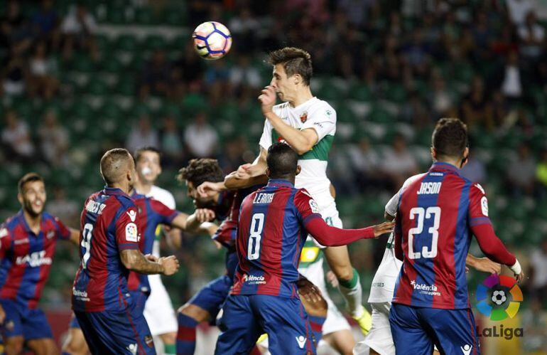 El delantero del Elche C.F. Guillermo remata de cabeza rodeado de rivales