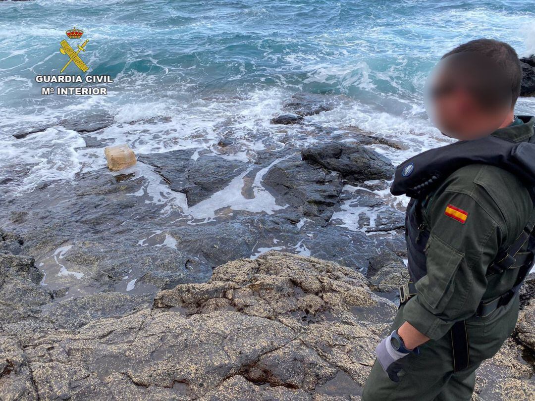 Un agente de la Guardia Civil observando algunos de los fardos encontrados.