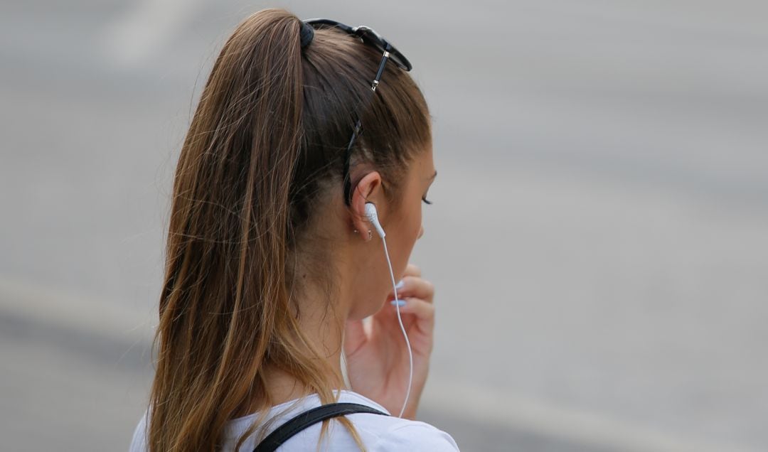 Una joven escuchando música en su teléfono móvil.