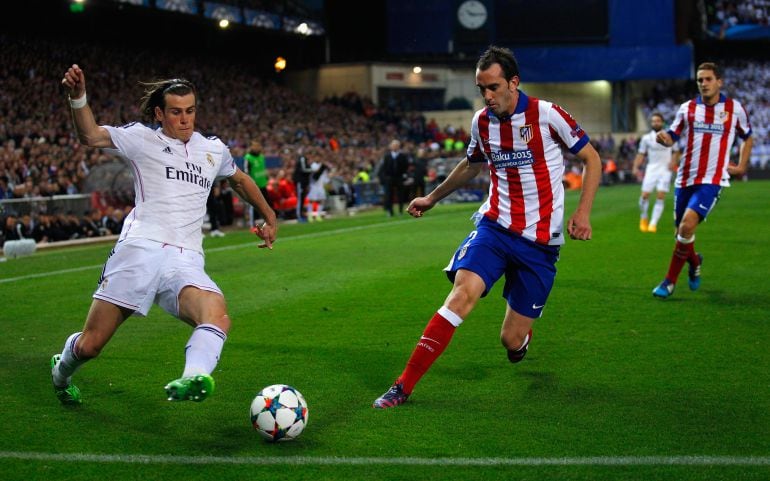 Diego Godín pelea el balón ante Gareth Bale.