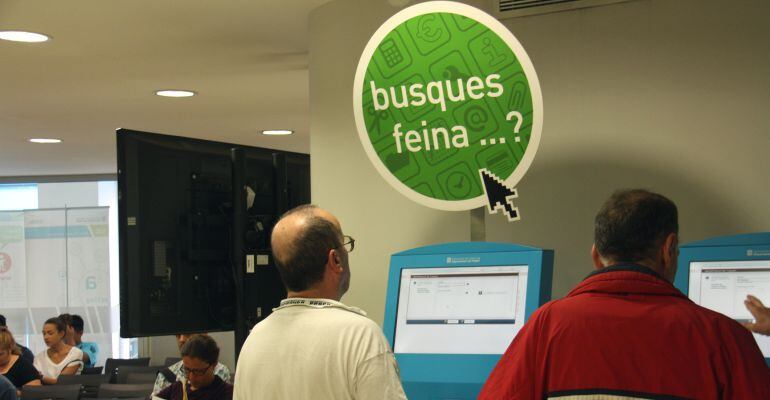 Dos nois en una de les màquines de cerca de feina en una oficina del Servei d'Ocupació de Catalunya