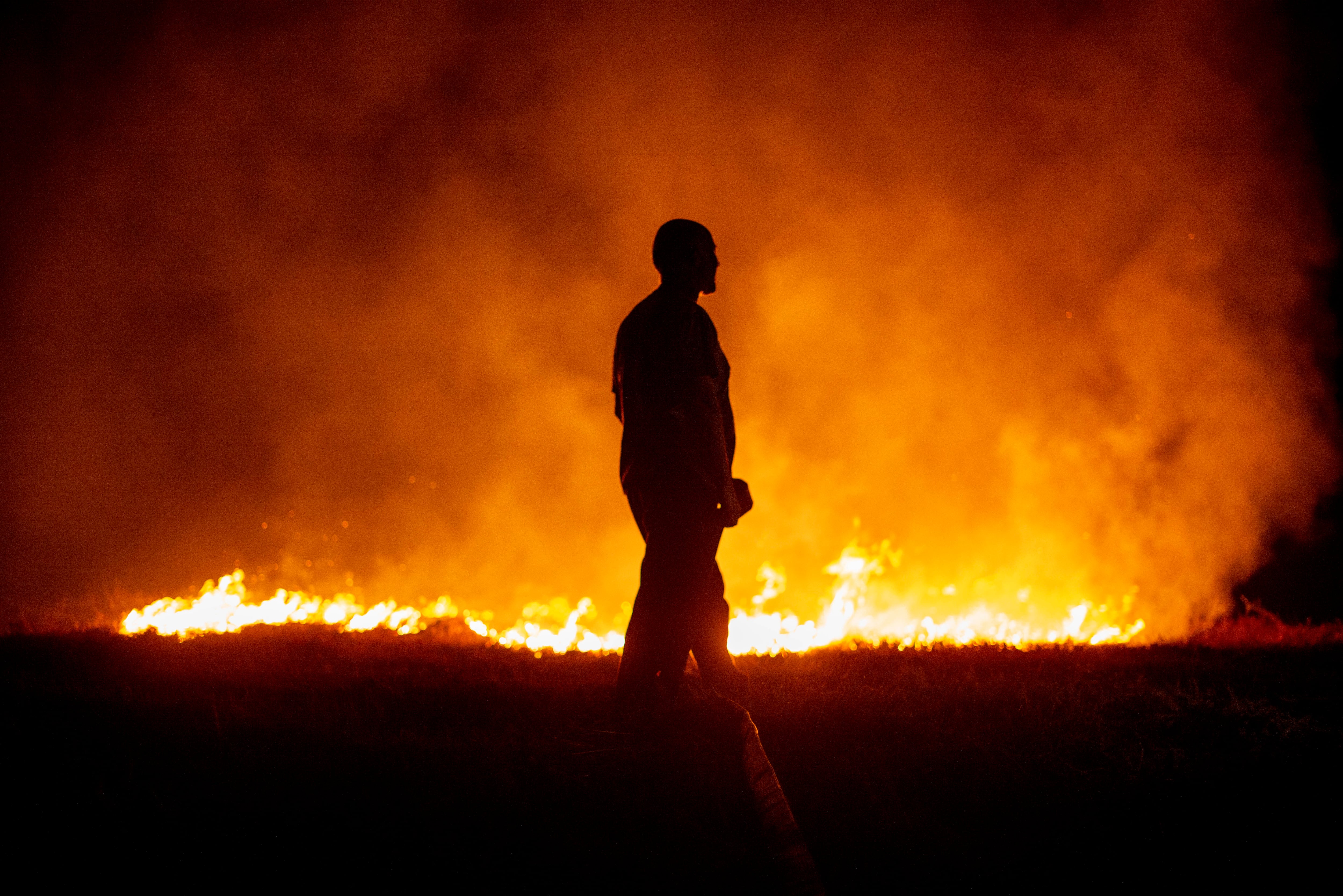 Un vecino ante las llamas mientras colabora en las labores de extinción del incendio de Cures, en Boiro, A Coruña