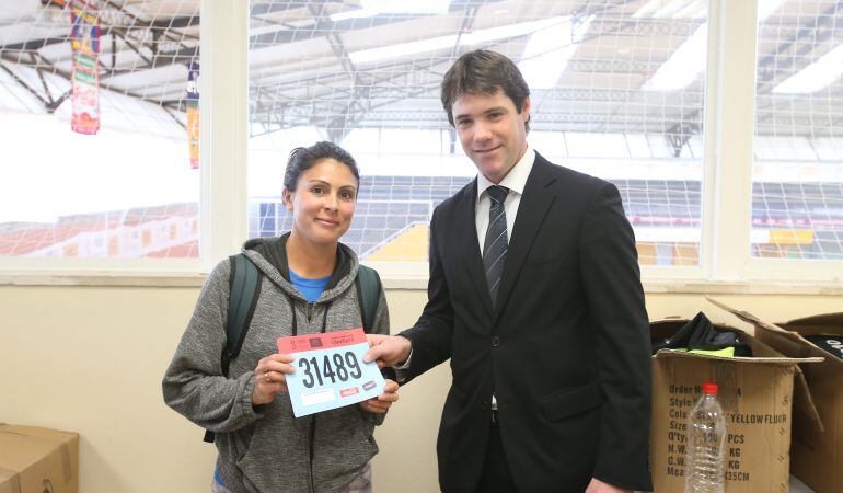 El delegado municipal de Deportes, david Guevara, entrega su dorsal a una de las participantes este domingo en la carrera popular Parque Vega de Triana