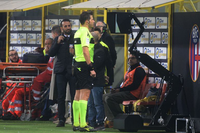 Un árbitro mira a una pantalla durante un partido en el Calcio