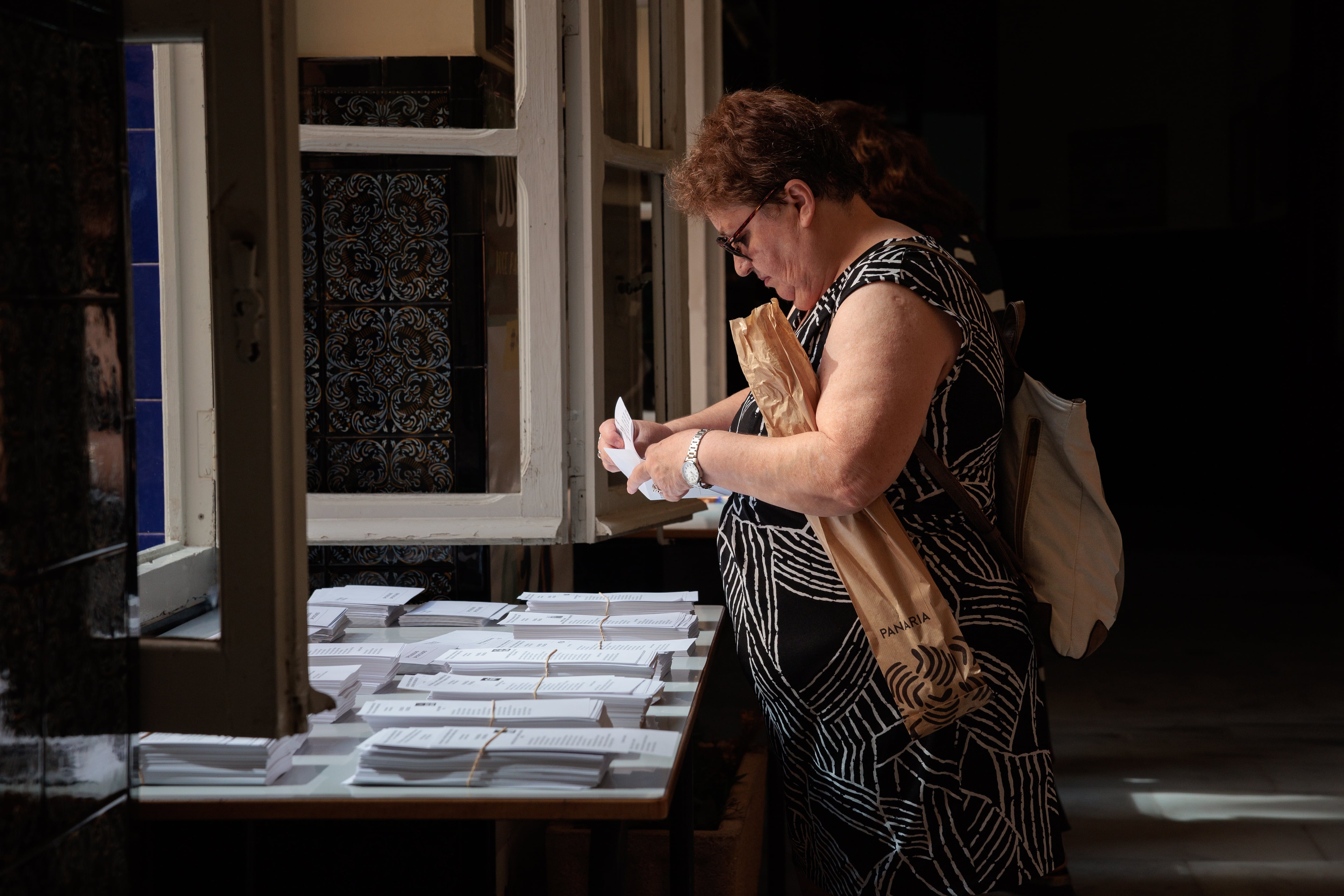 GRAFCVA4805. VALENCIA, 23/07/2023.- Una mujer escoge una papeleta en un colegio electoral cuando más de 3.700.000 personas están llamadas a votar en la Comunitat Valenciana en las elecciones generales del 23j para elegir 33 diputados (16 por Valencia -uno más que hace cuatro años-, 12 por Alicante y 5 por Castellón) y 12 senadores (cuatro por cada circunscripción). EFE/Biel Aliño
