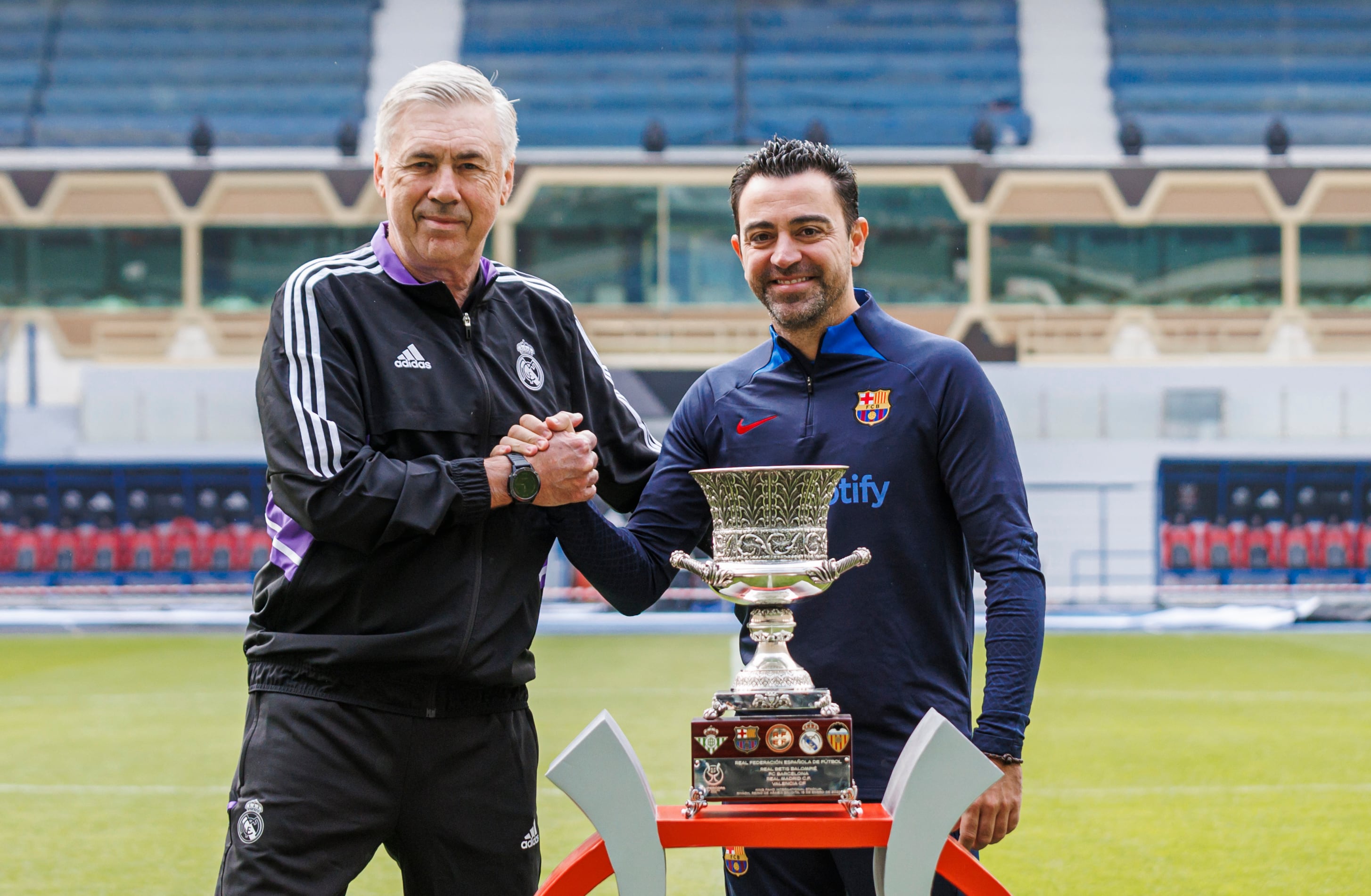 Xavi y Ancelotti se saludan junto a la Supercopa de España.