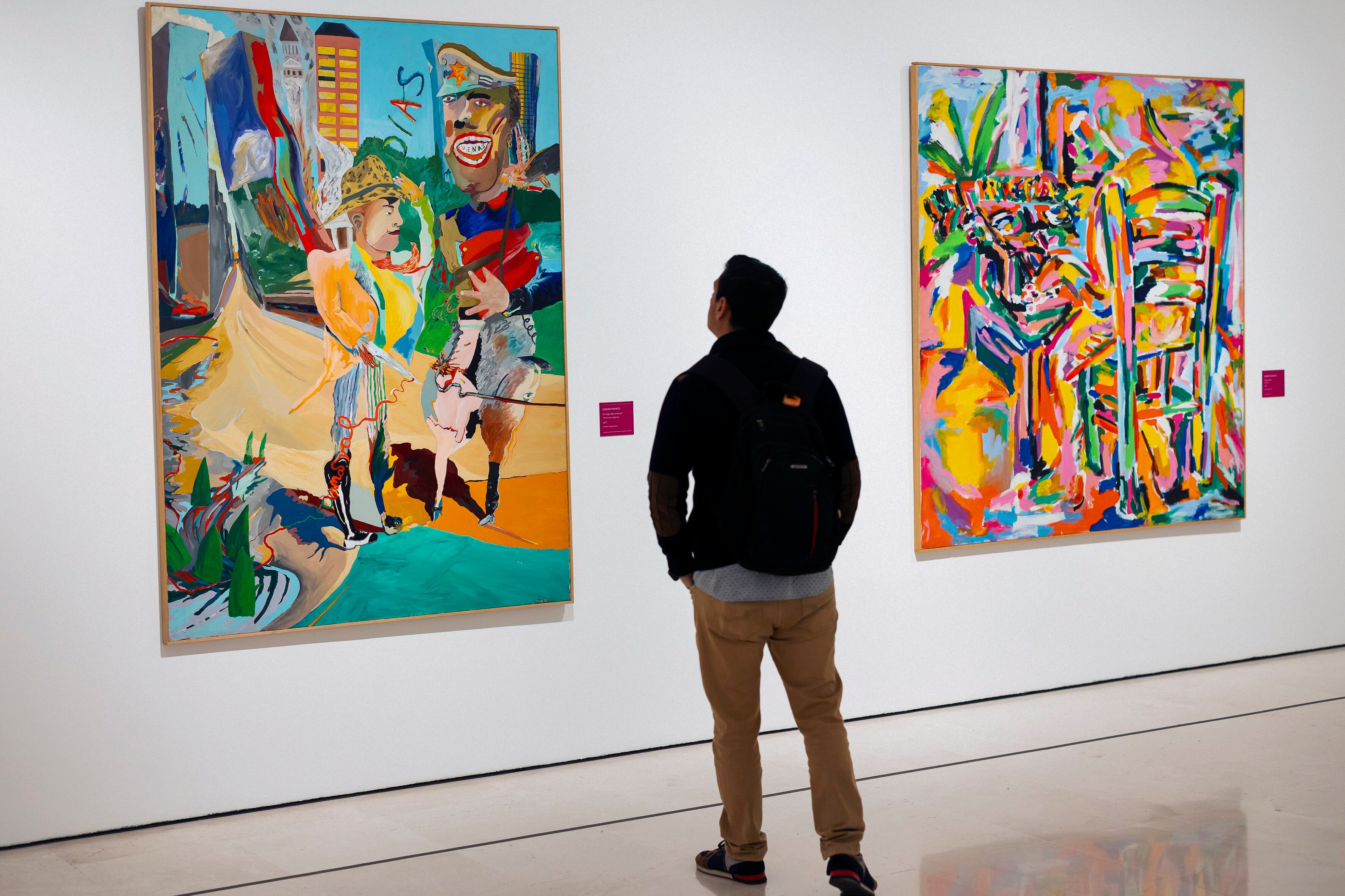 MÁLAGA, 31/03/2025.-Un hombre mira las obras &#039;El mago del carnaval&#039;(i) de Carlos Franco y &#039;Maquinando&#039;(d) de Manolo Quejido durante la presentación de la exposición &#039;Pintura liberada. Joven figuración española de los 80&#039; en el Museo Carmen Thyssen en Málaga, este lunes. EFE/Carlos Díaz
