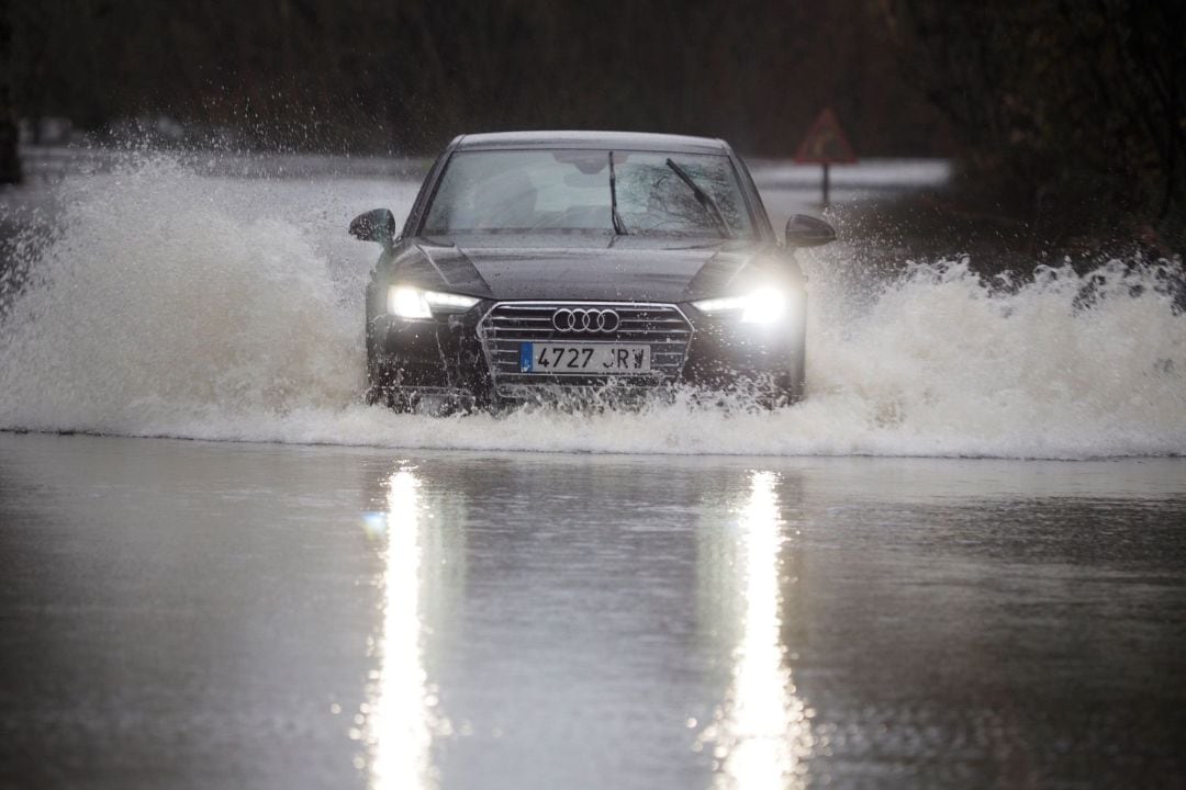 Un coche cruza la carretera LU-P-1701, en Muimenta, Lugo, inundada por el agua de los ríos Pequeño y Miño. 