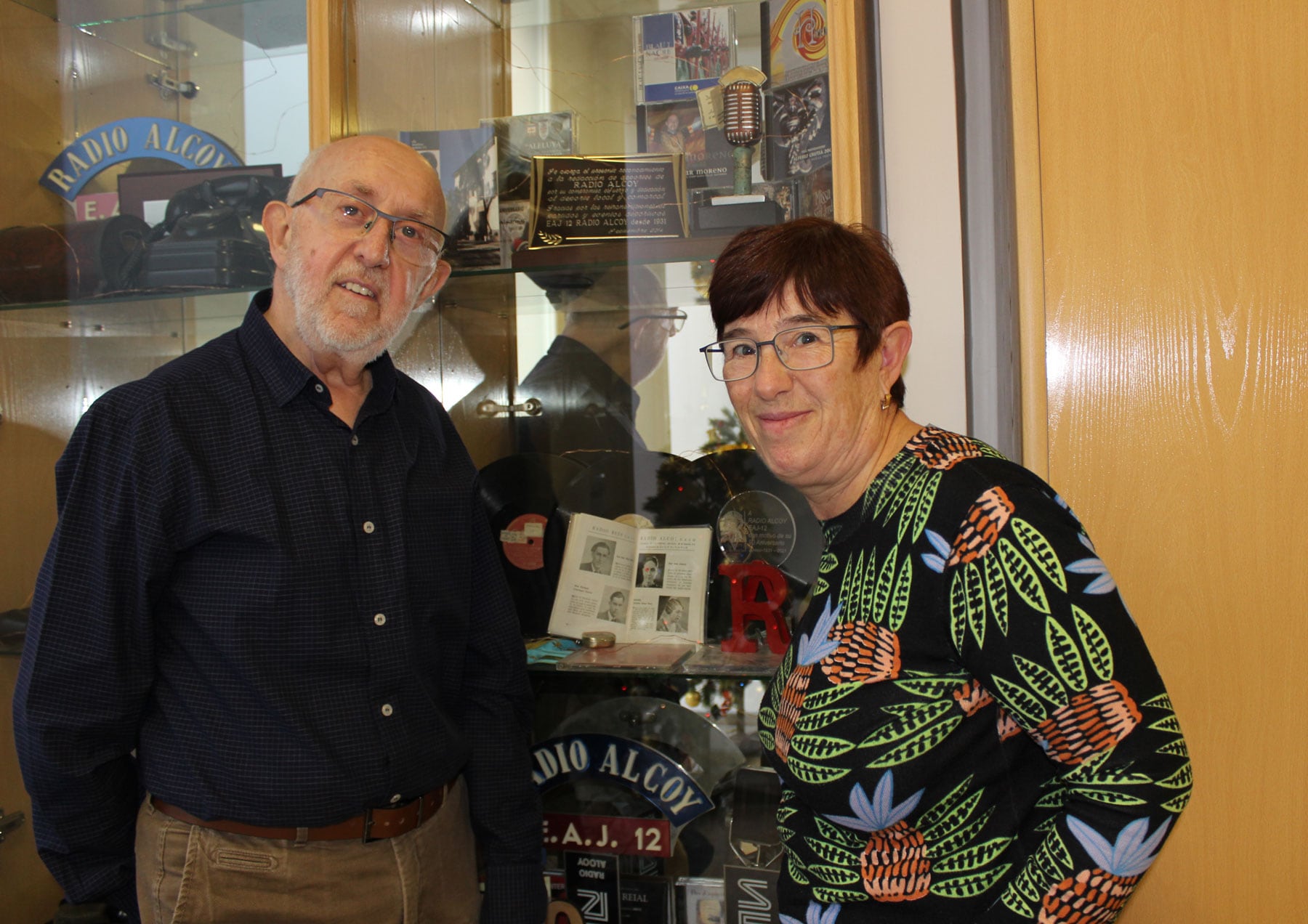 Vicent Agulló e Inma Llopis, con la guía al fondo, dentro de la pequeña vitrina-museo de Radio Alcoy