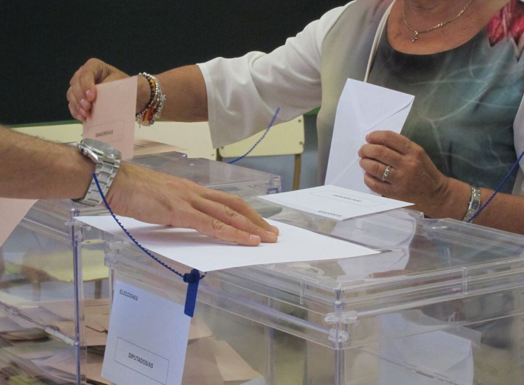 Una mujer deposita su papeleta electoral en una urna.