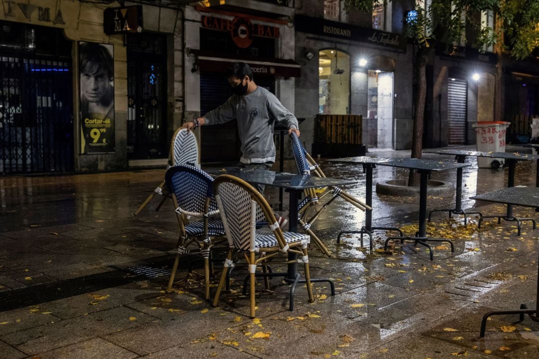 Un camarero recoge la terraza de su negocio en la primera jornada de toque de queda en Madrid