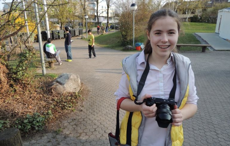 Pauline sonríe con su cámara en el polideportivo de Stuttgart donde viven los refugiados