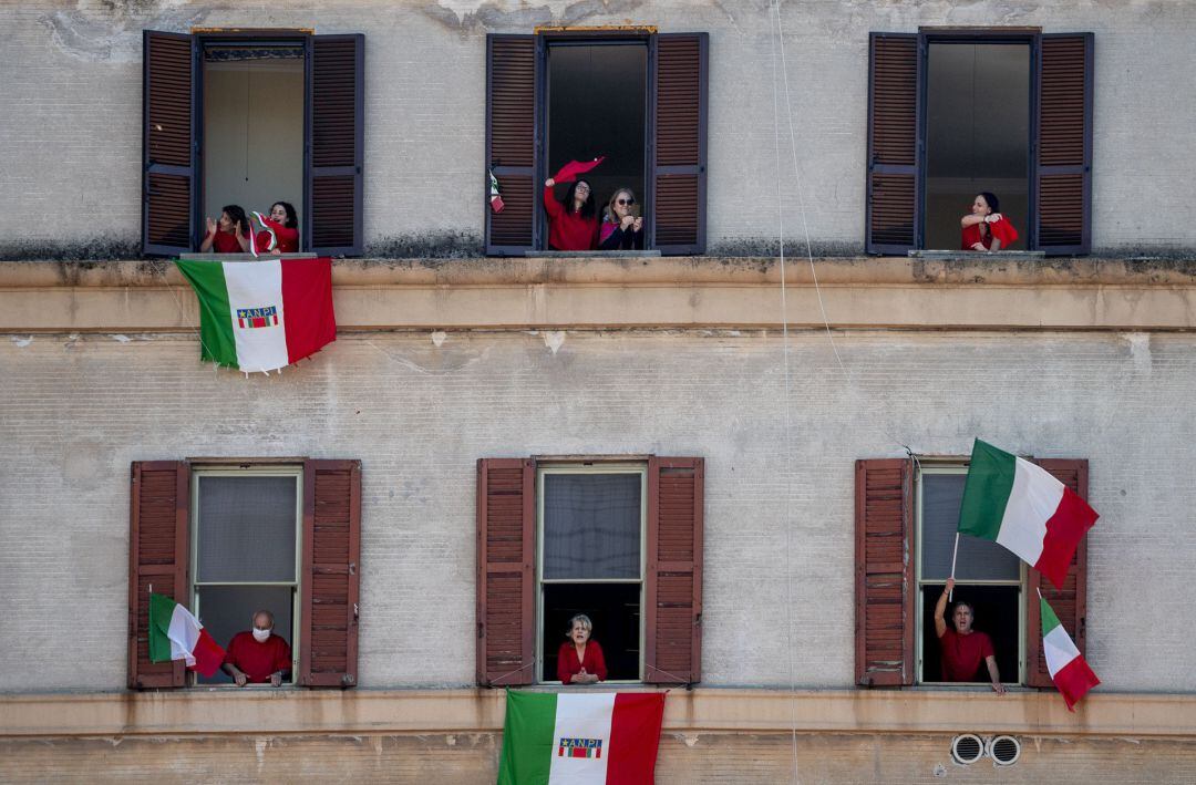 Italianos desde sus balcones agitando banderas de Italia.