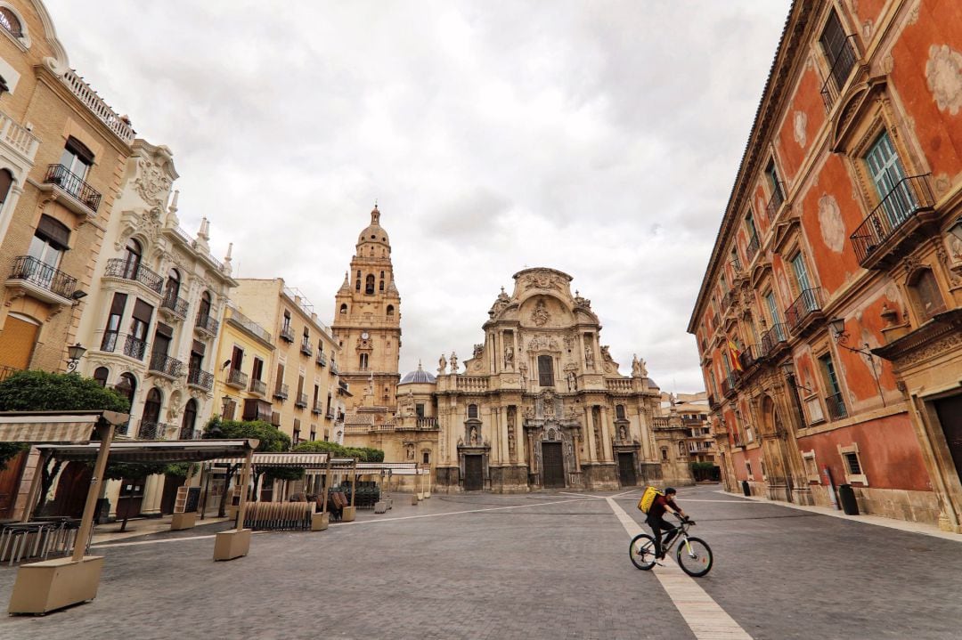 Un repartidor cruza en bicicleta la desierta Plaza del Cardenal Belluga de Murcia, Durante el vigésimo segundo día del estado de alarma decretado en todo el país para frenar la expansión del coronavirus