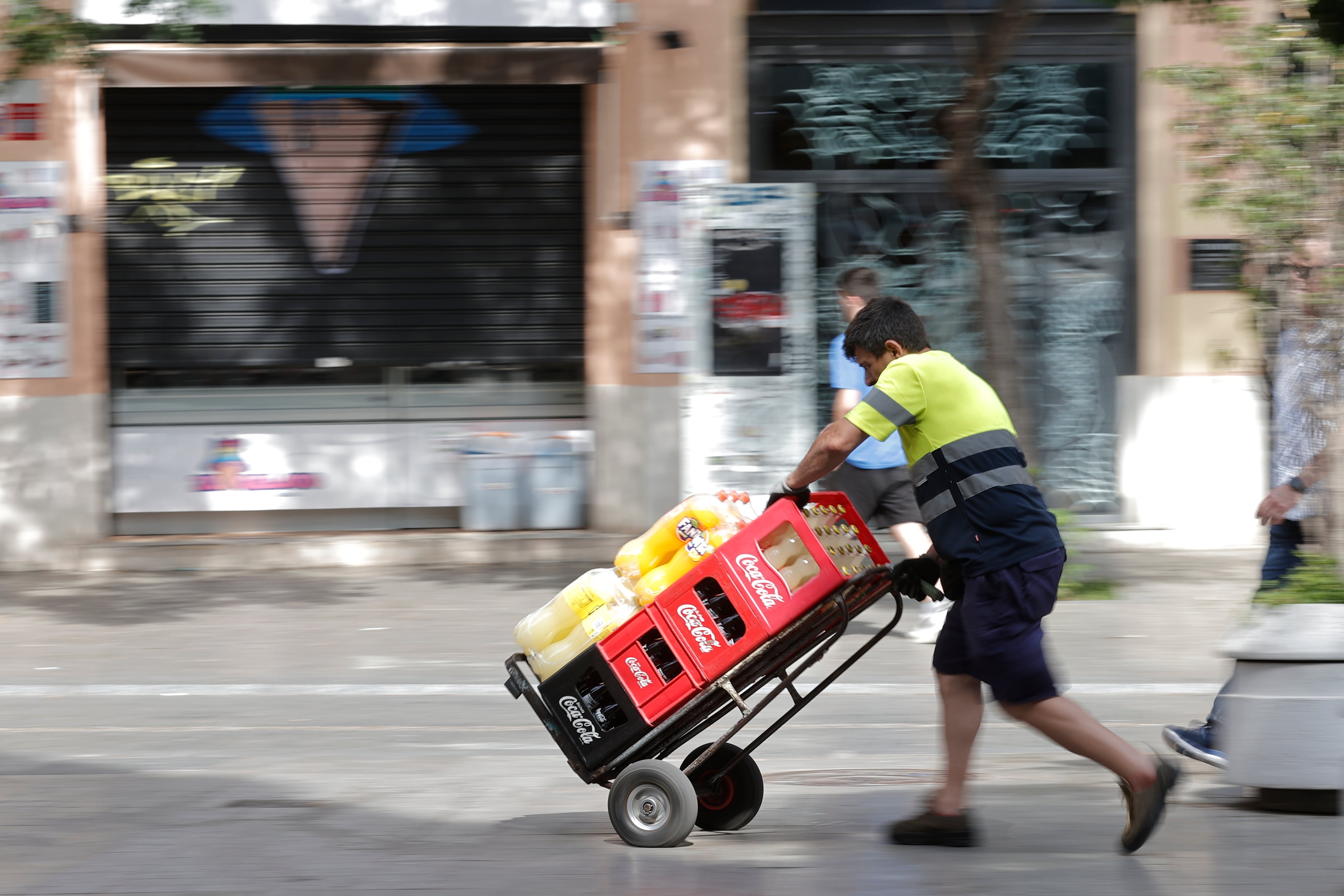 Un trabajador lleva una carretilla repleta de bebida