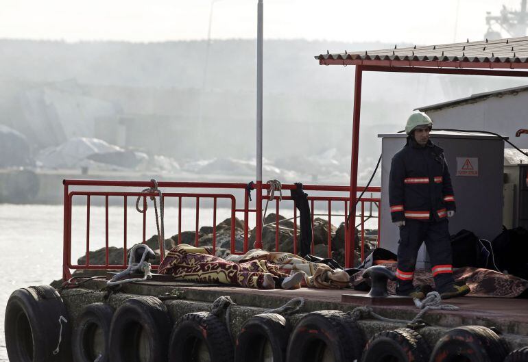 Un miembro de los equipos de rescate camina ante los cadáveres recuperados